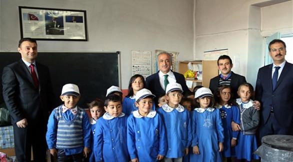 رئيس جامعة أتاتورك عمرو شوماكلي في صورة إلى جانب تلاميذ مدرسة عزيزية (زمان)