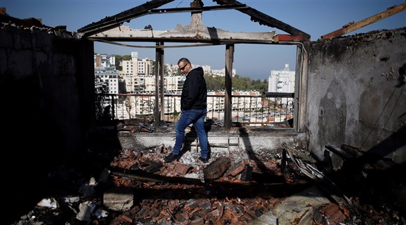 رجل يعاين أضرار الحريق في حيفا، فلسطين المحتلة (رويترز)