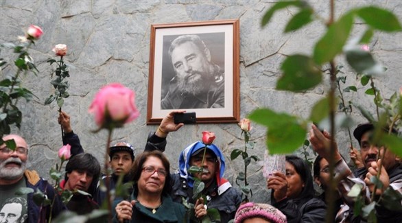 من كولومبيا، يرفعون الورود بجانب صورة للزعيم الراحل فيدل كاسترو (أ ف ب)