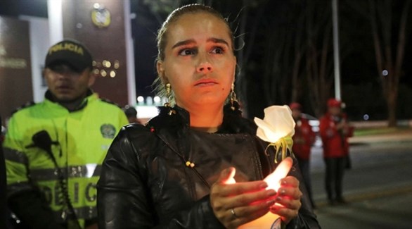 كولومبية تحمل شمعة حداداً على ضحايا التفجير في بوغوتا (انفو باي) 