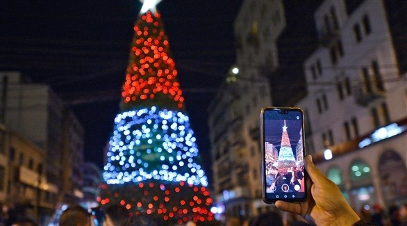 شخص يصور شجرة عيد الميلاد المنصوبة في طرابلس شمال لبنان (اي بي ايه)