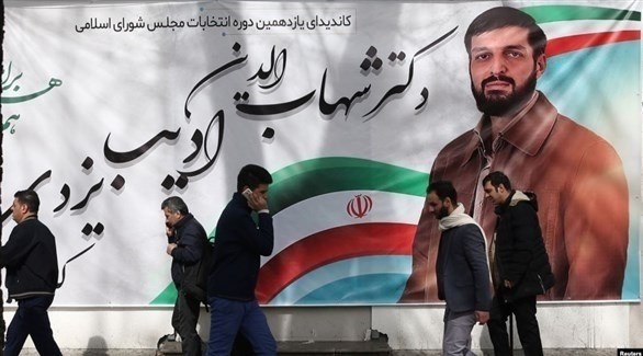 إيرانيون أمام ملصق انتخابي لأحد المرشحين للبرلمان (الحرة)