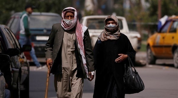 سوريان يرتديان كمامة في وسط دمشق (رويترز)