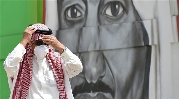 رجل مرتدياً الكماماة يعدل في حط شماغه في أحد الشوارع السعودية (أرشيف)