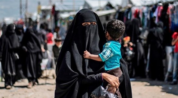 سيدة تحمل طفلها في مخيم الهول بسوريا (أرشيف)
