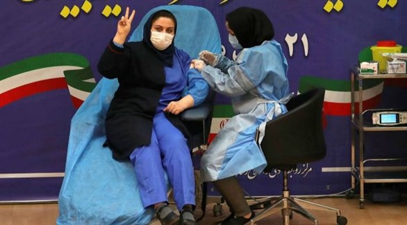 ممرضة تُطعم إيرانية ضد كورونا في طهران (أرشيف)