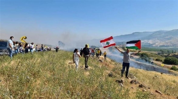 لبناني يرفع علم لبنان وفلسطين خلال وقفة احتجاجية على الحدود (تويتر)