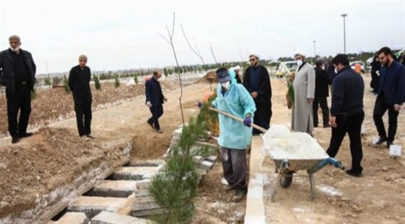عامل يهيل التراب على قبور ضحايا كورونا في مقبرة إيرانية (أرشيف)