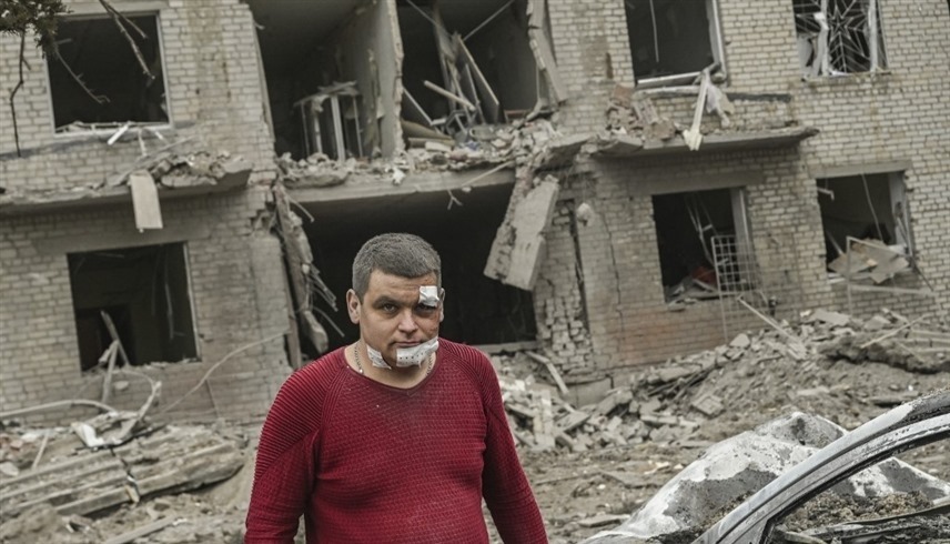 أوكراني مصاب بجروح أمام مبنى مدمر في سلوفيانسك.(أف ب)